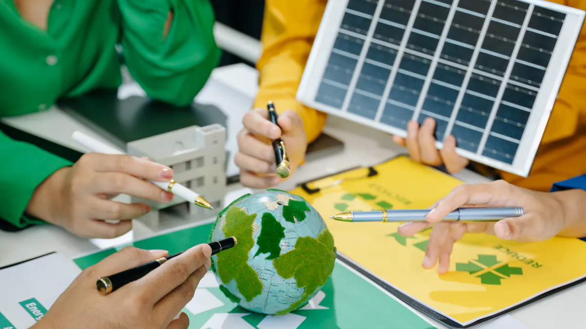 Team around a table with a solar panel, a green globe and recycling charts