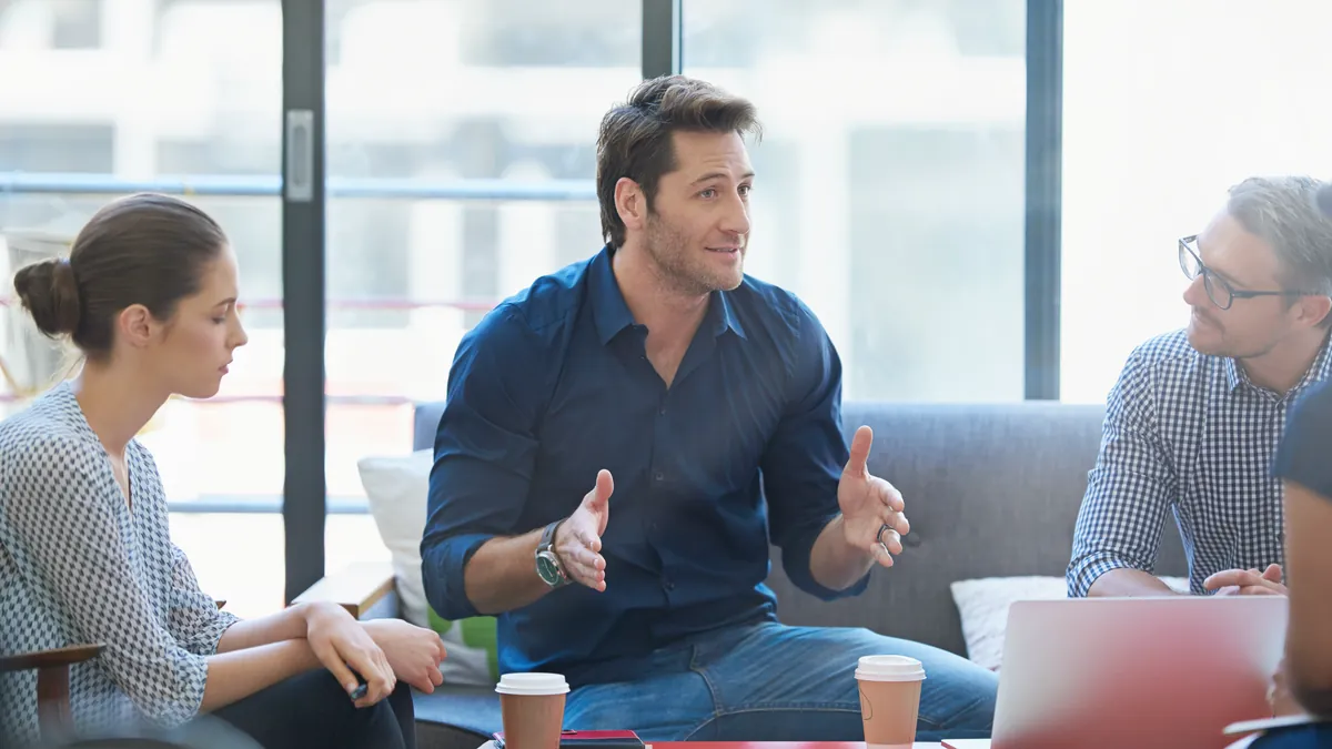 Four colleagues in conversation around a low table in a bright office