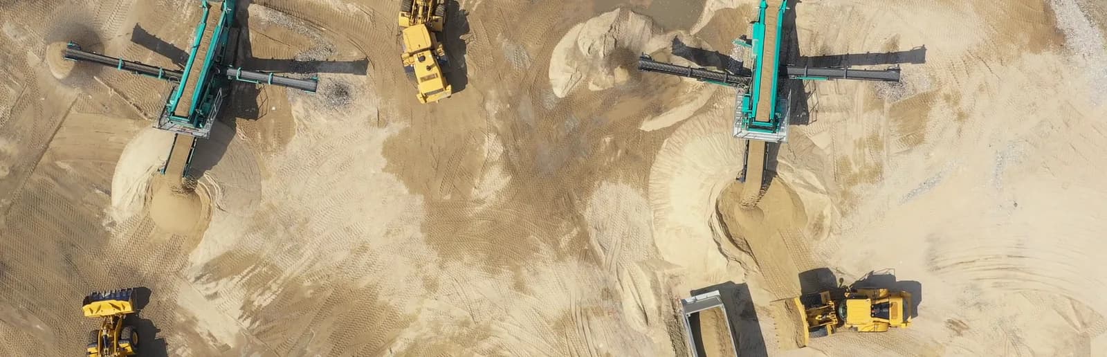 Senkrechte Luftaufnahme einer Sandgrube im Betrieb, mit Siebanlagen, Radladern und Muldenkippern